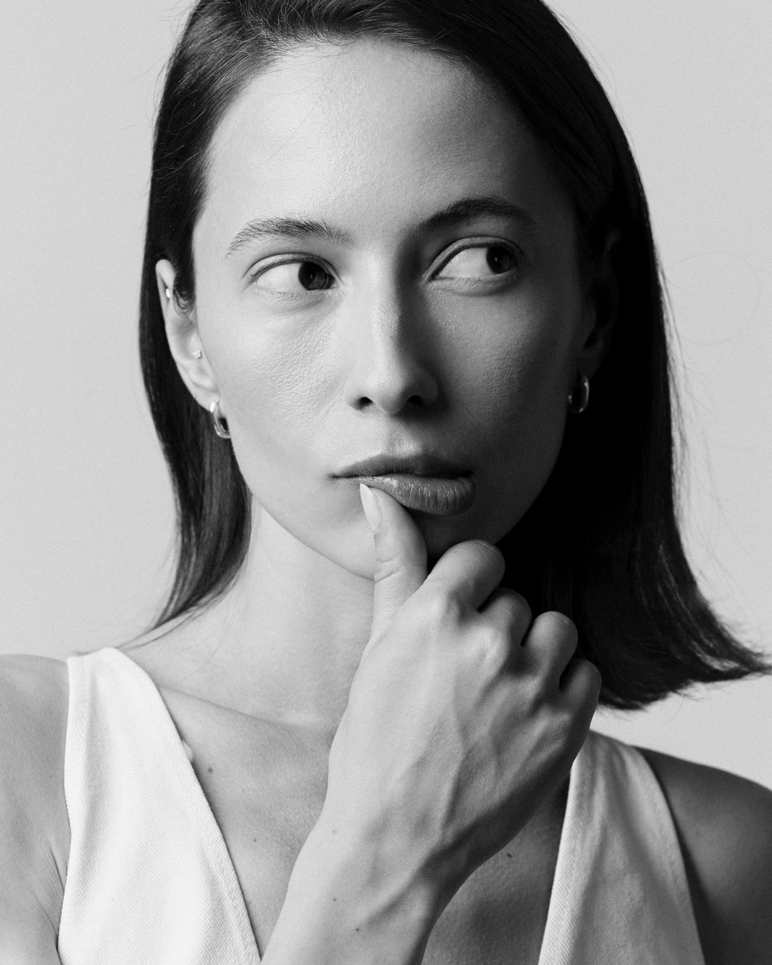 Black-and-white close-up portrait of a woman resting her finger on her lips