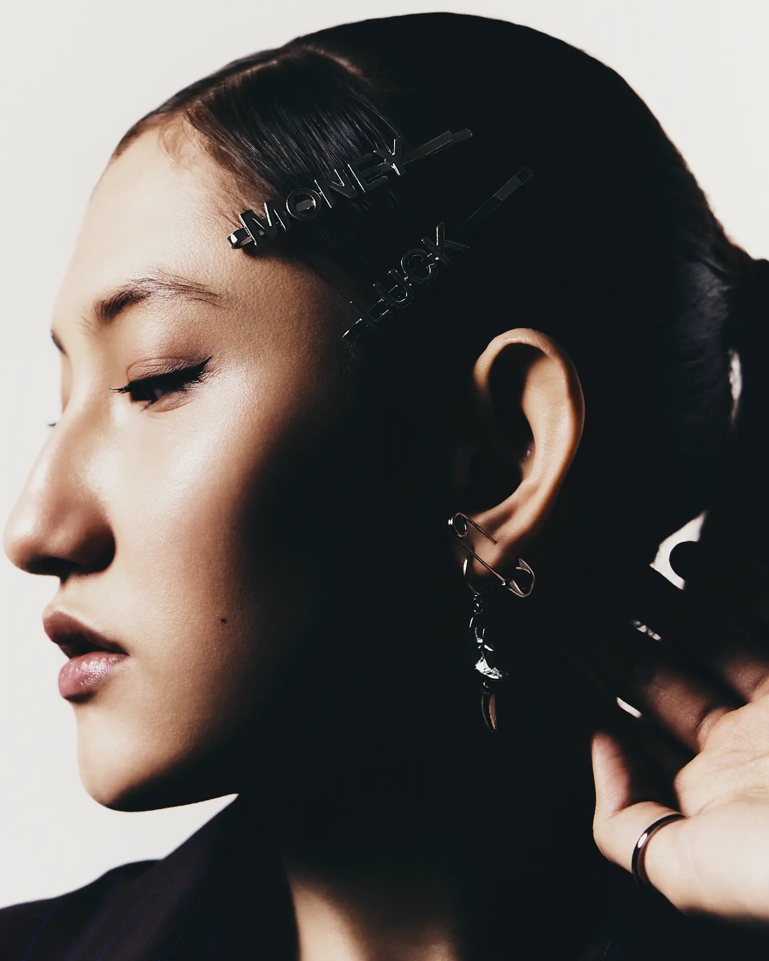 Close-up profile of a woman with dark hair pinned back, wearing statement hair clips and earrings
