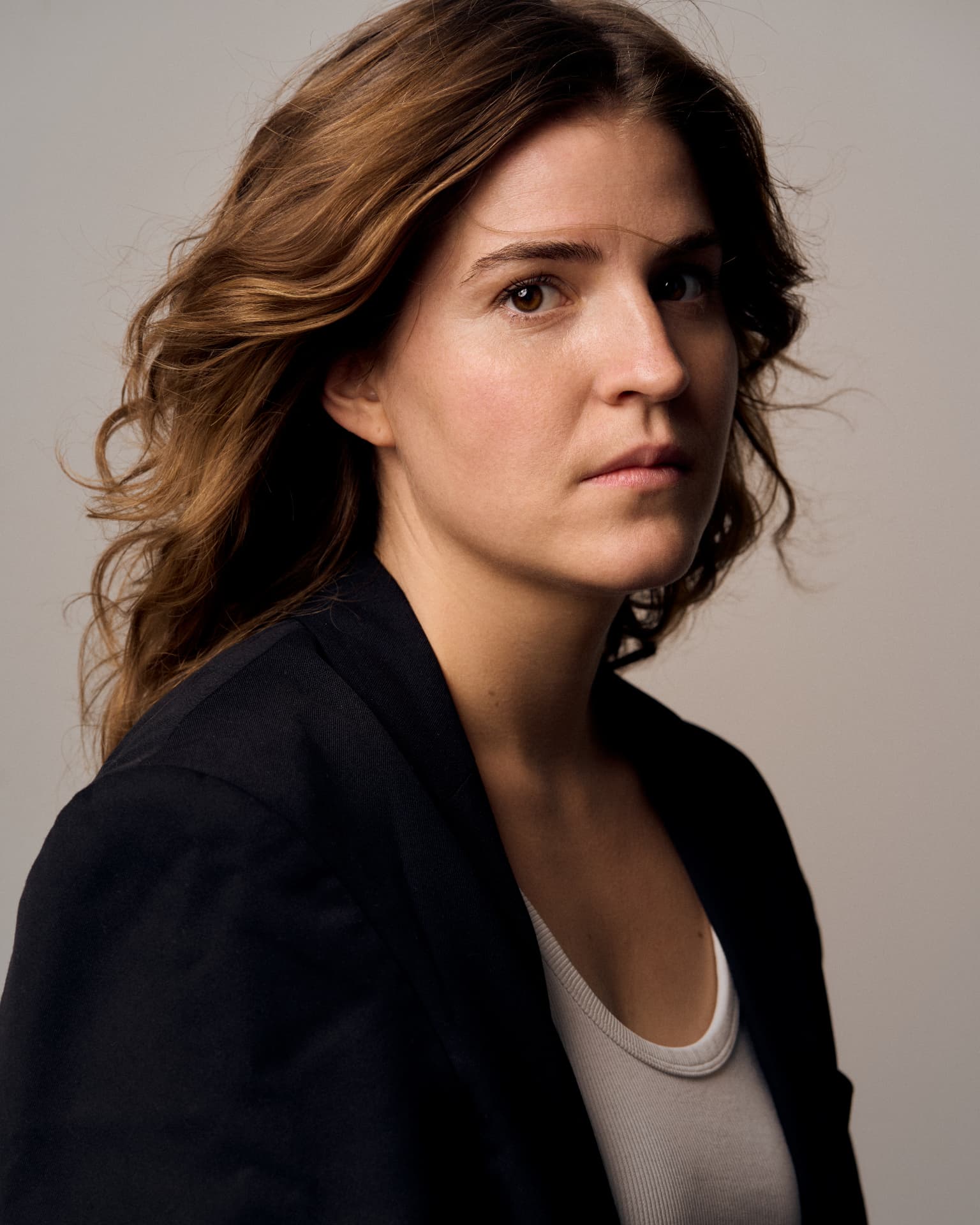 Close-up portrait of a woman in a dark blazer against a grey background