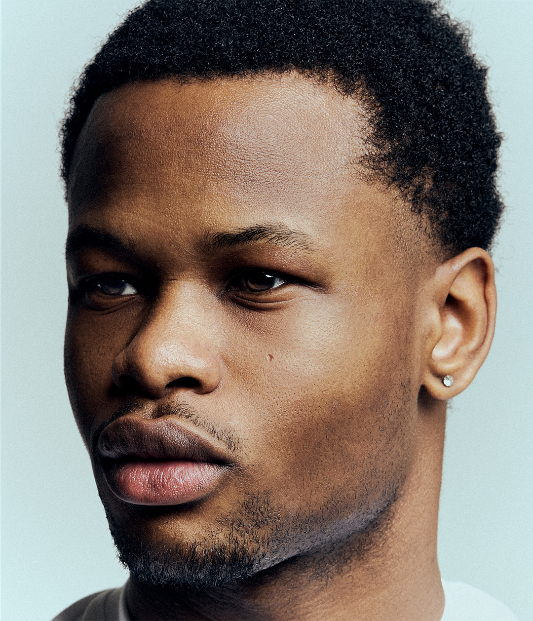 Close-up portrait of a young man looking to the side against a pale blue background