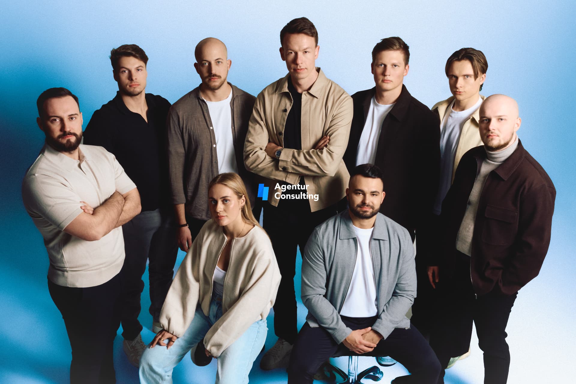 Group portrait of a consulting team in neutral tones against a blue backdrop