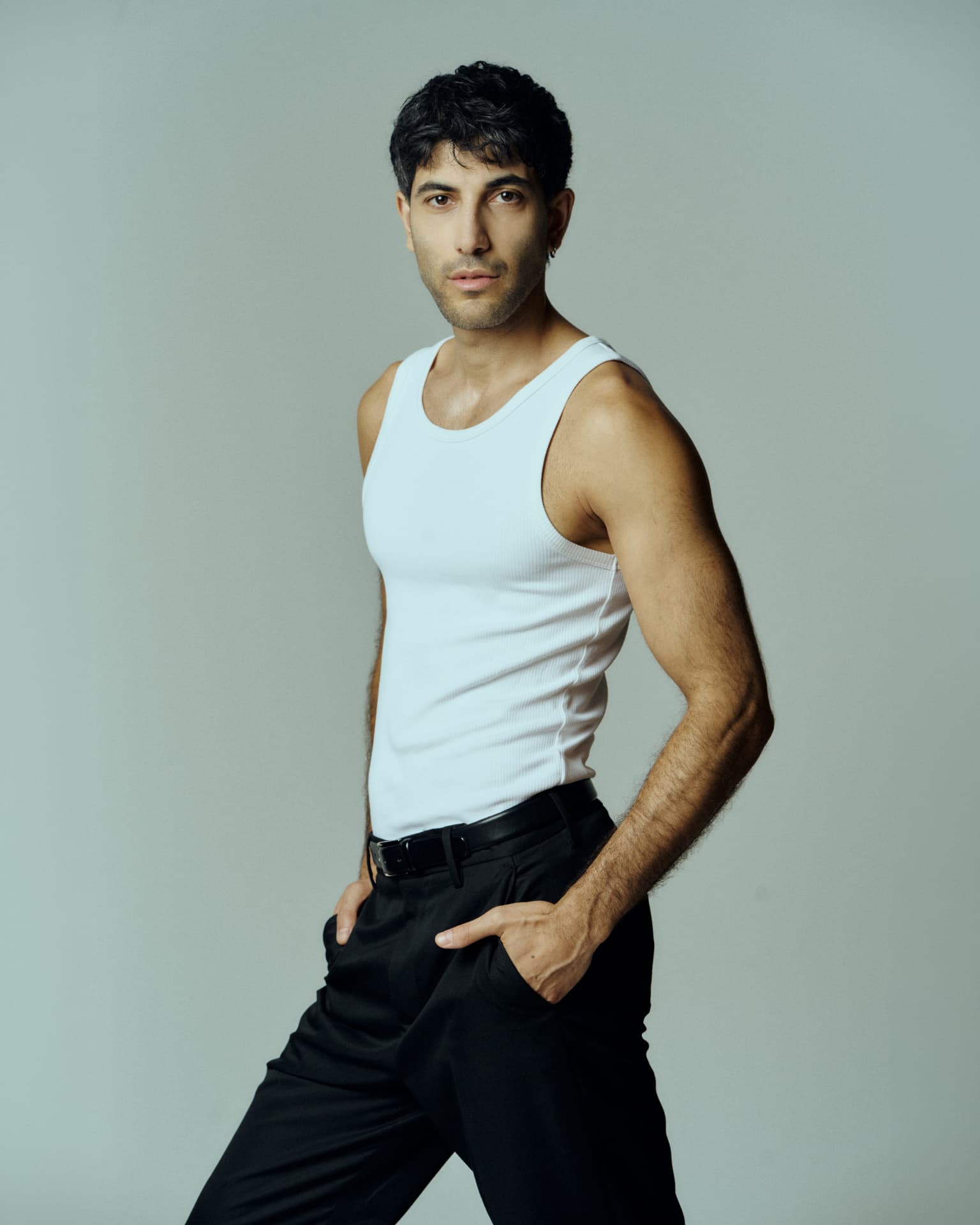 Studio portrait of a man in a white tank top and black trousers