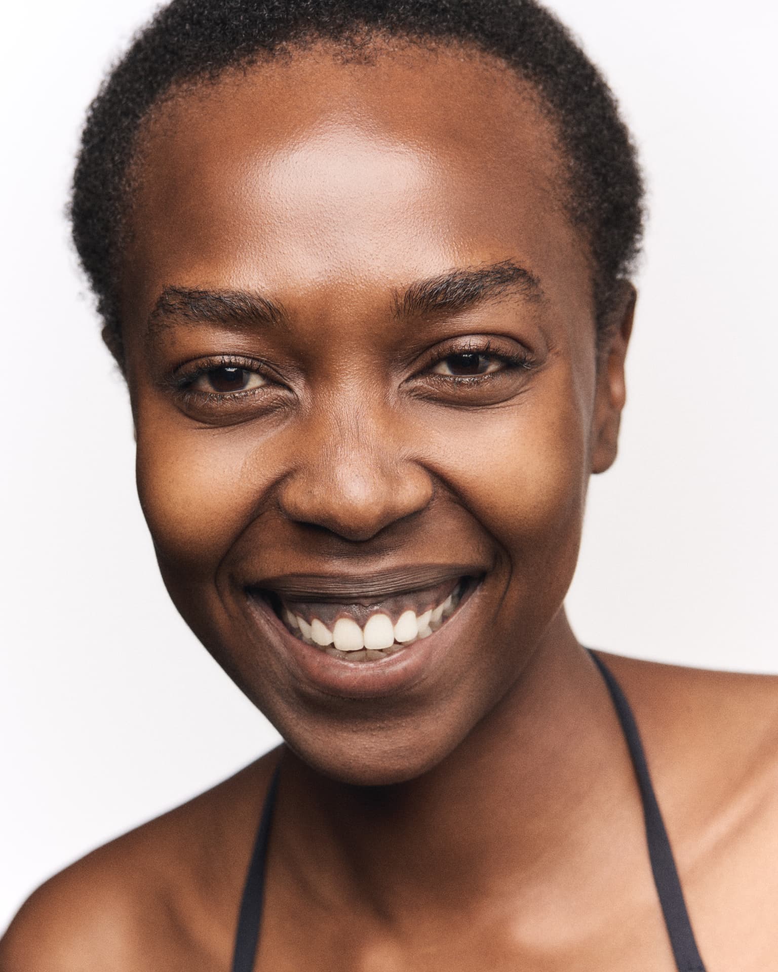 Close-up portrait of a smiling woman with short hair against a bright background
