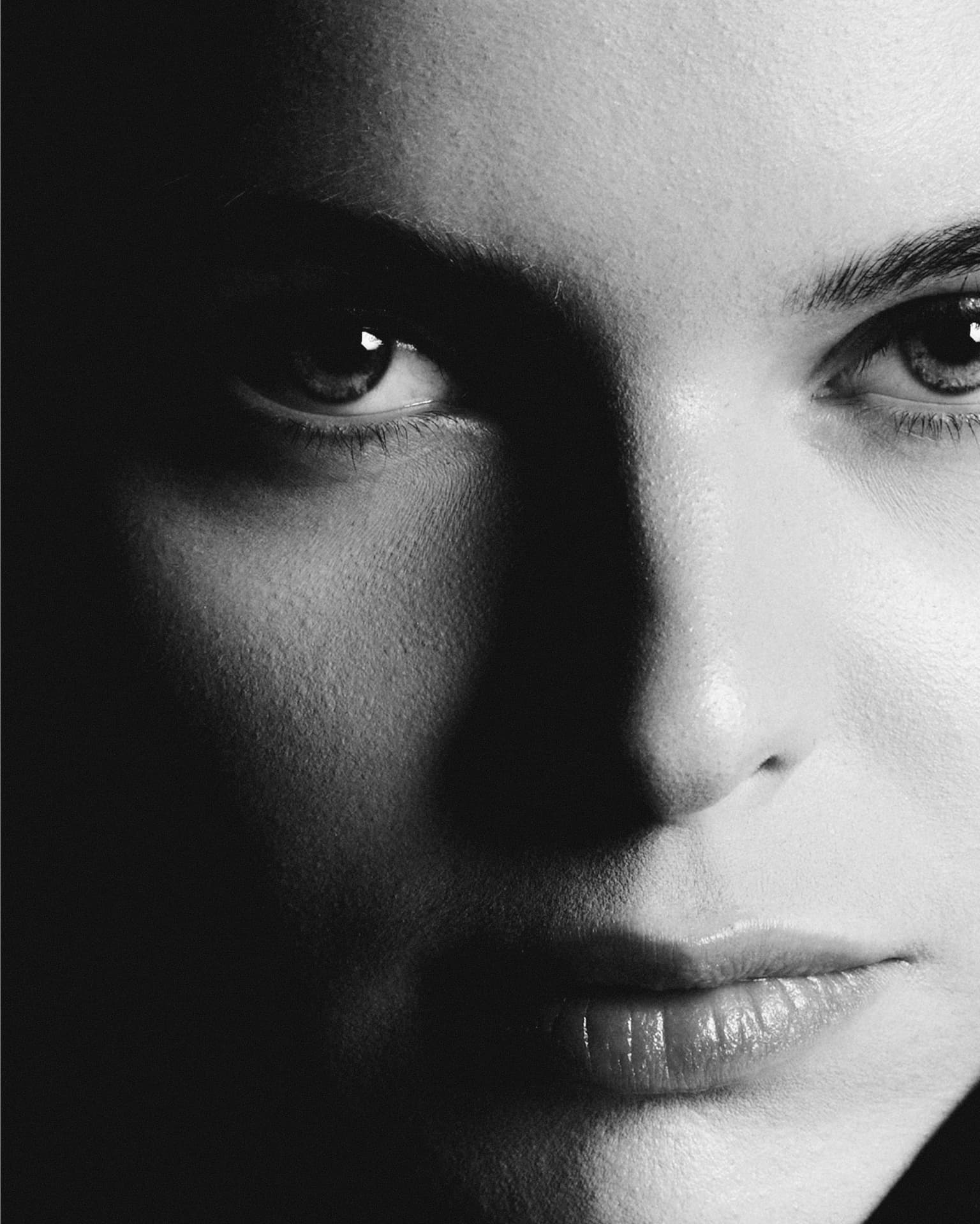 Black-and-white extreme close-up of a woman's face, half in shadow