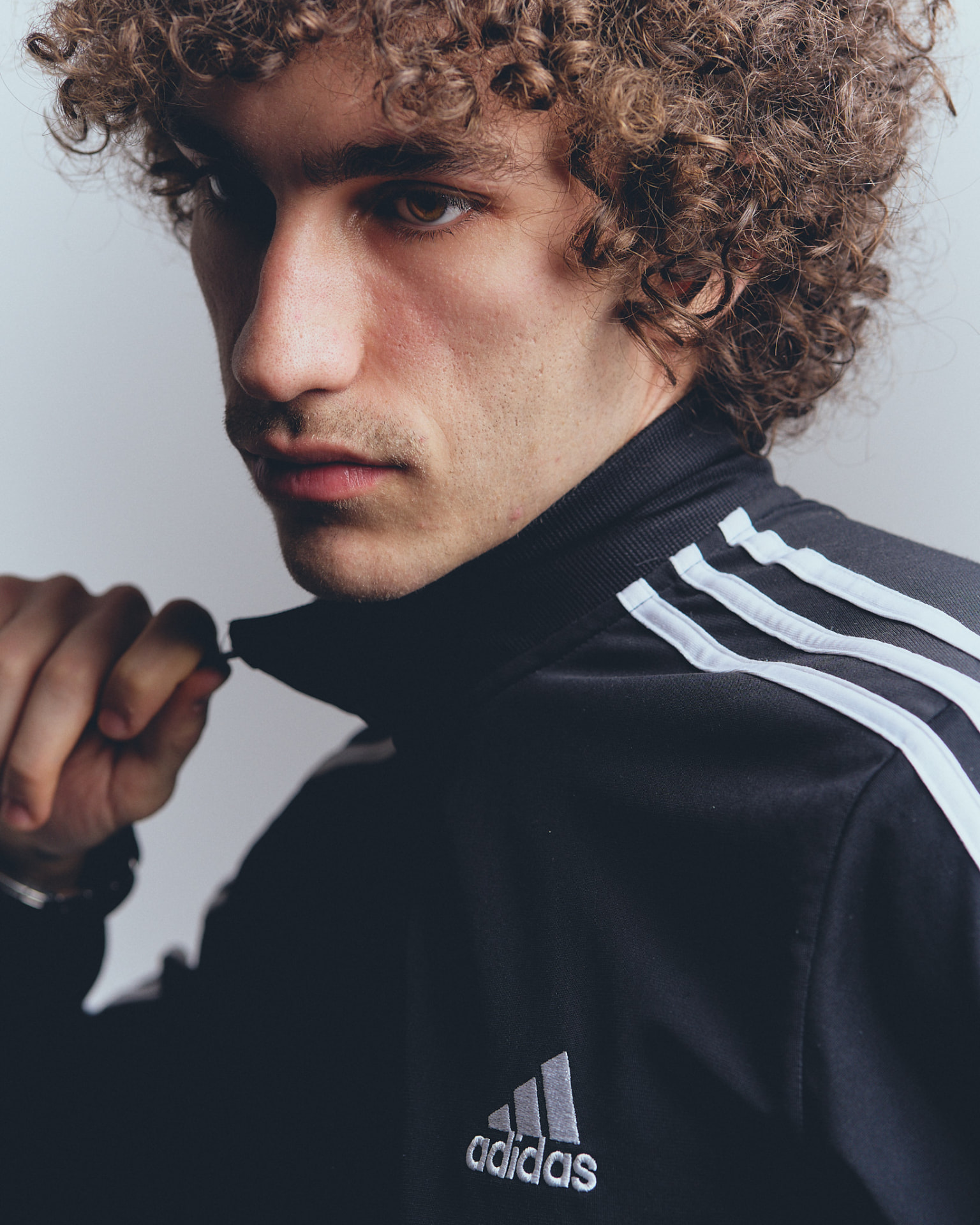 Close-up portrait of a young man in a black track jacket, looking off-camera