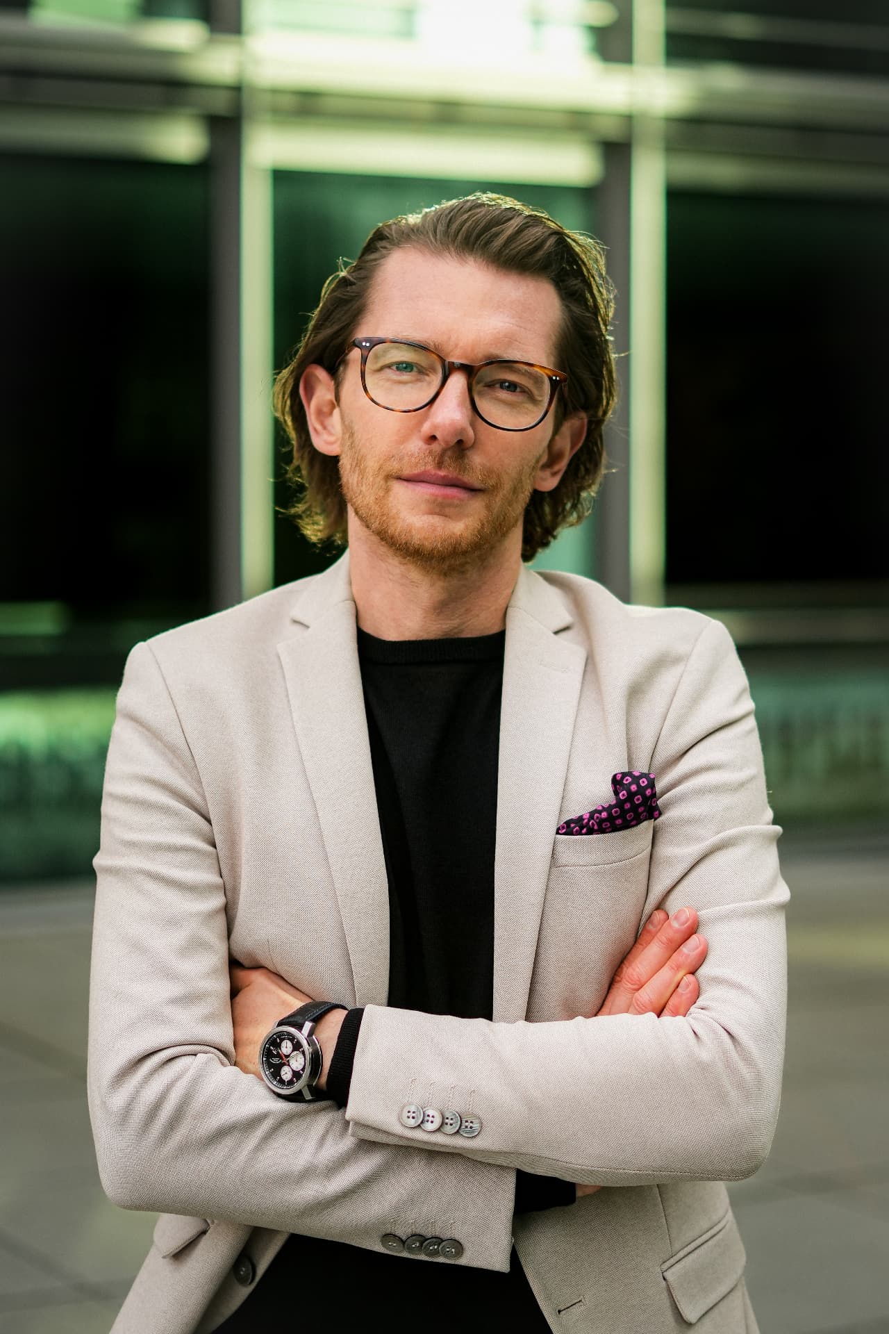 Portrait of a man in glasses and a light blazer, arms crossed